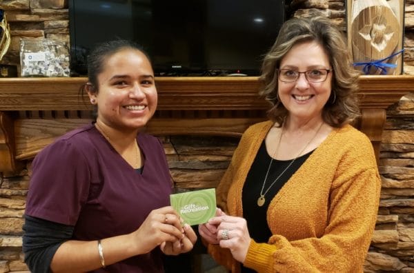 NOVO's dental hygienist presents client with gift card for monthly draw